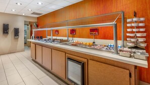 A buffet counter with various food items, a refrigerator, and a wall-mounted clock. - Best Western Plus Scottsdale Thunderbird Suites (Scottsdale)