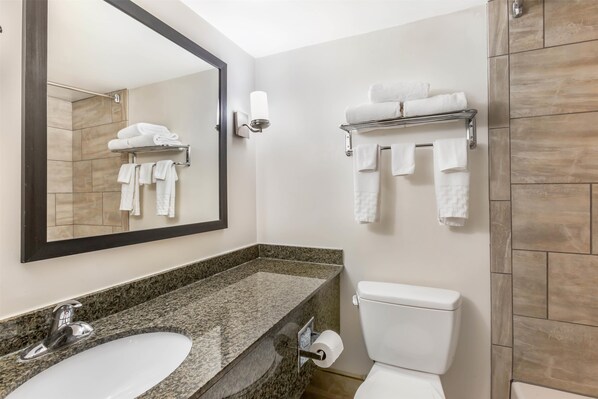 Un baño con lavamanos, inodoro, toallero y espejo.