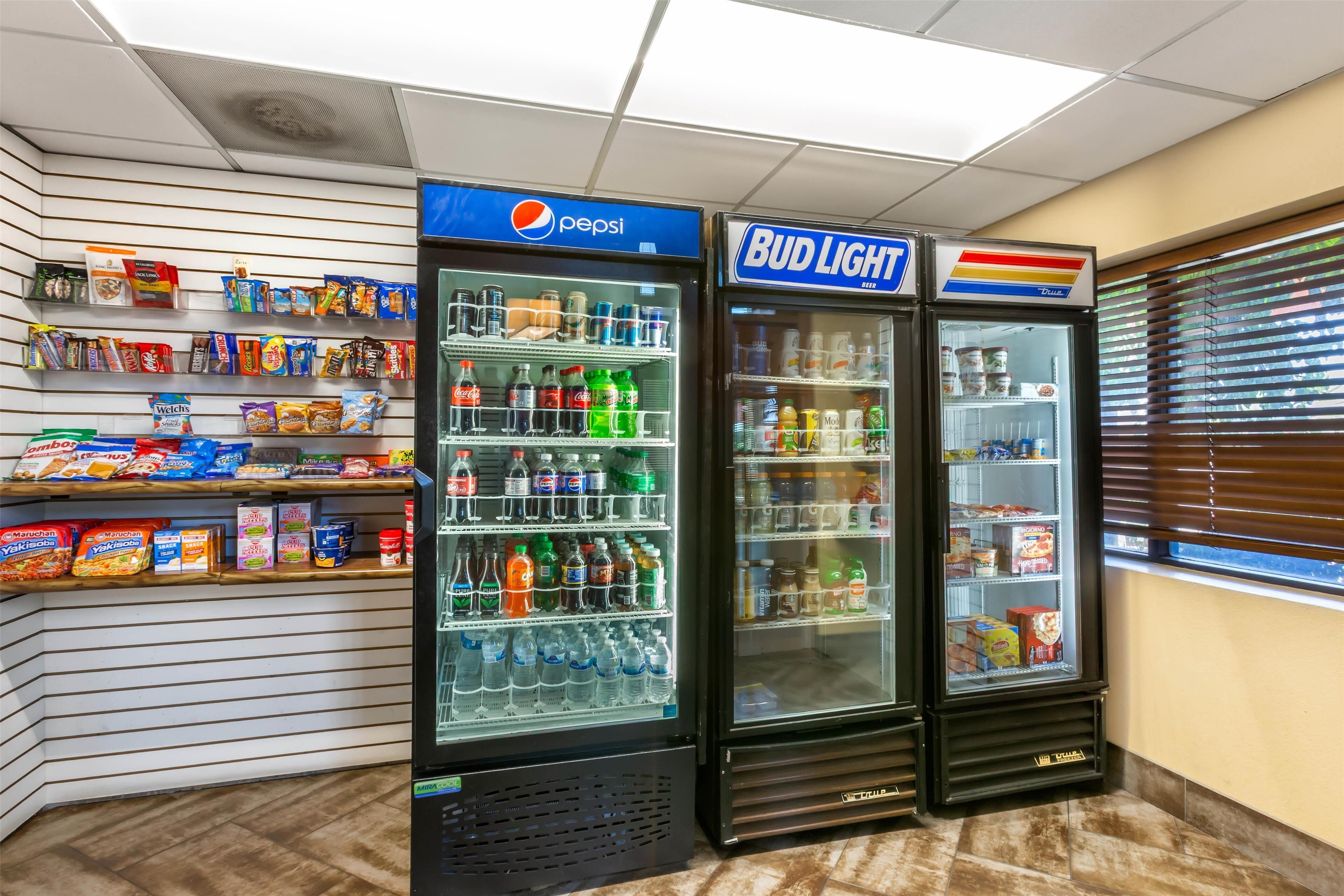A vending area with Pepsi and Bud Light refrigerators, snacks, and a window with blinds.