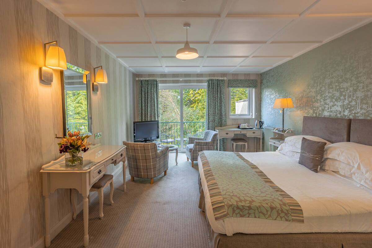 Une chambre d’hôtel équipée d’un lit, d’un bureau, d’une chaise, d’une télévision et offrant une vue sur l’extérieur.