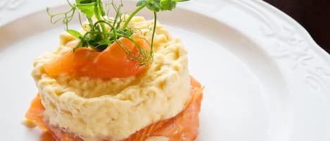 A dish with a creamy base, topped with smoked salmon and garnished with greens.