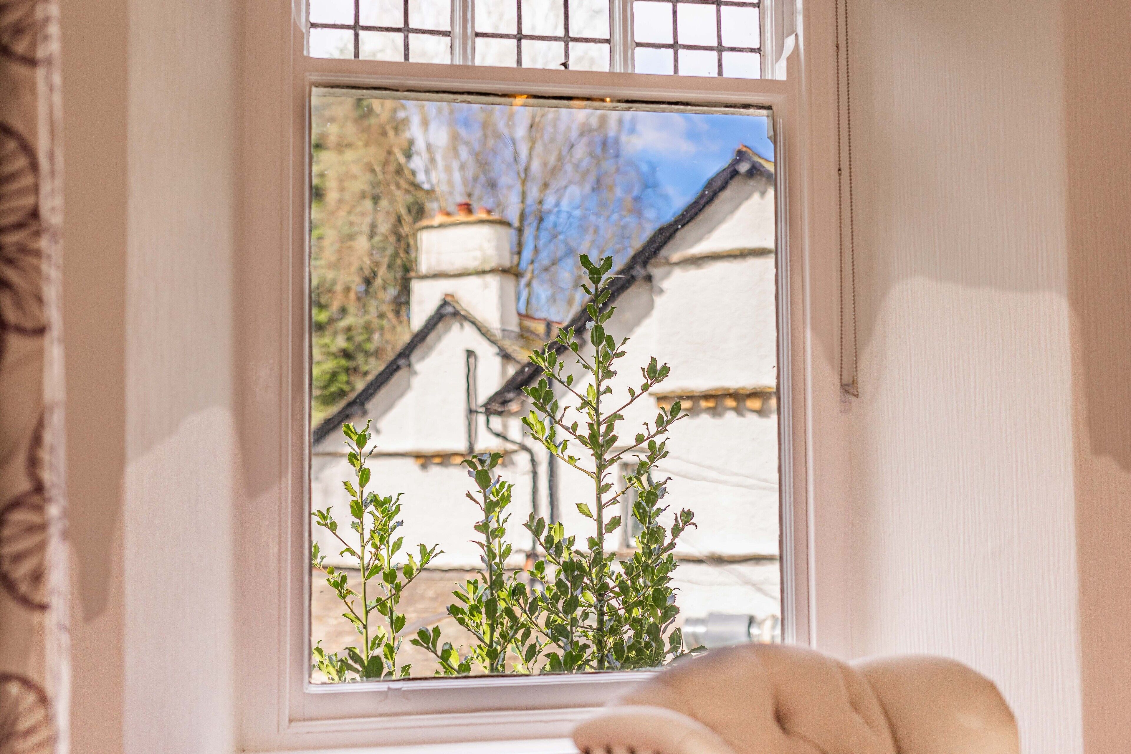 A window with a view of a white building with a sloped roof and a chimney.