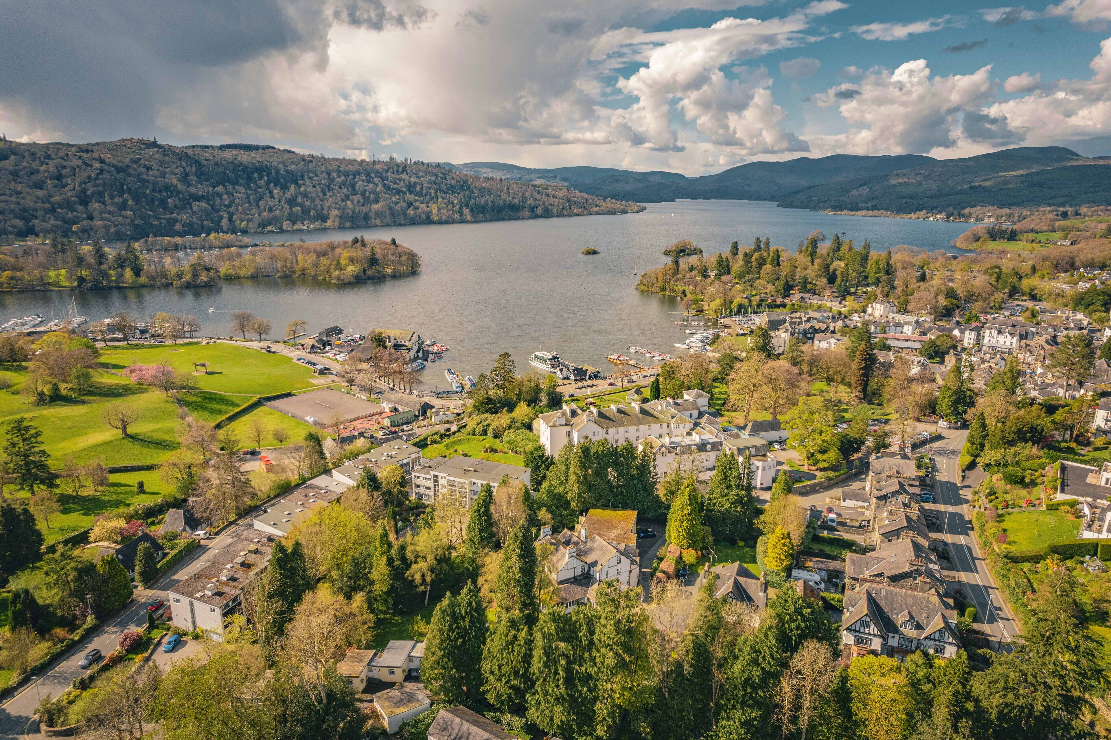 An aerial view of a town with a lake, surrounded by hills and greenery.
