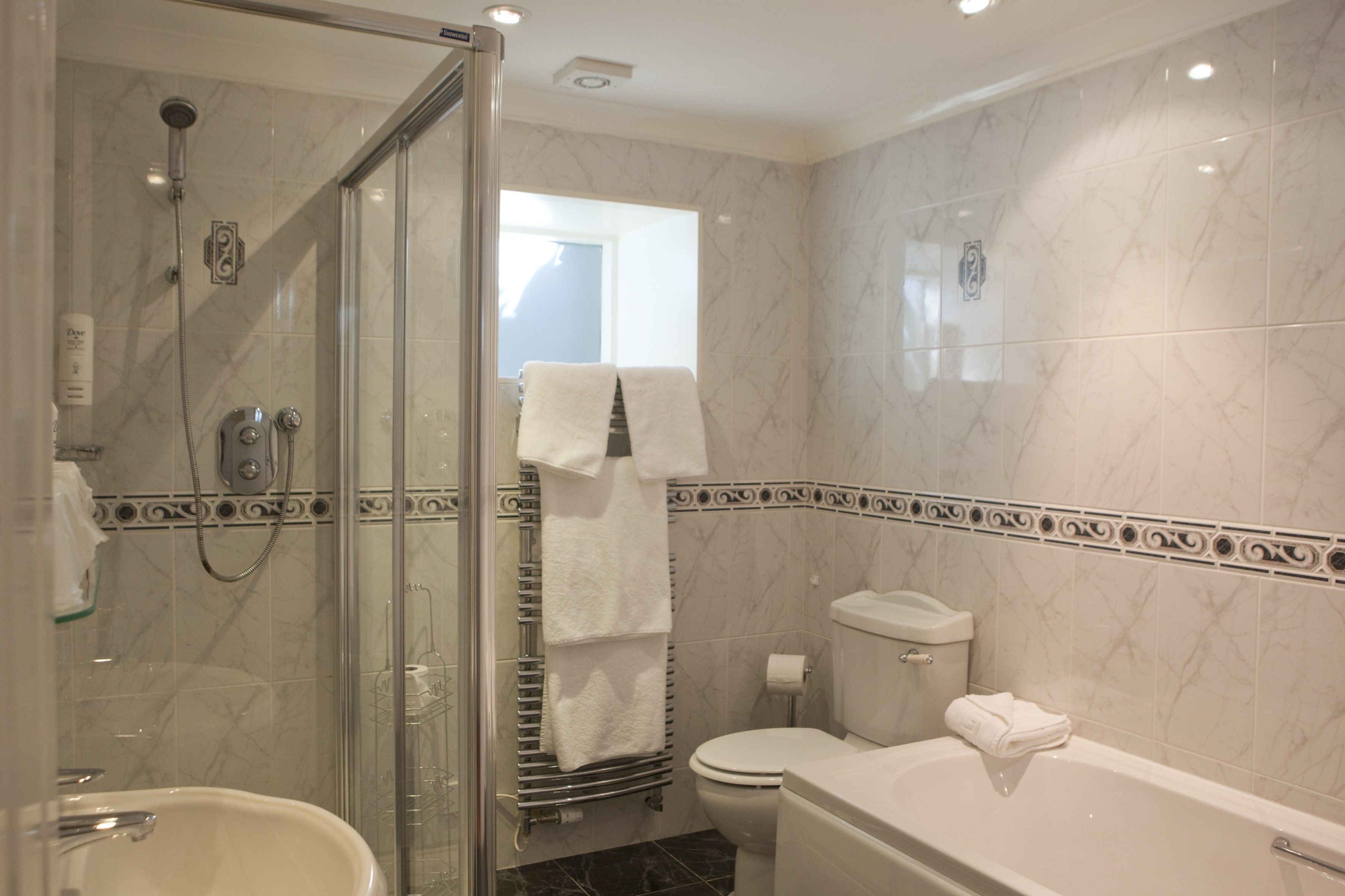 A bathroom with a glass-enclosed shower, a bathtub, a toilet, and a sink.