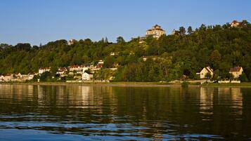 A lakeside view with a hilltop building and surrounding houses.