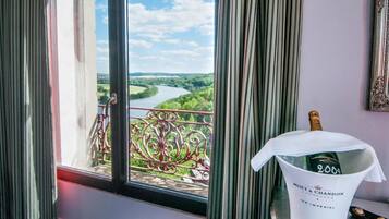 Une chambre avec vue sur une rivière et sur la verdure, une bouteille de champagne Moët & Chandon et un garde-corps décoratif en métal.