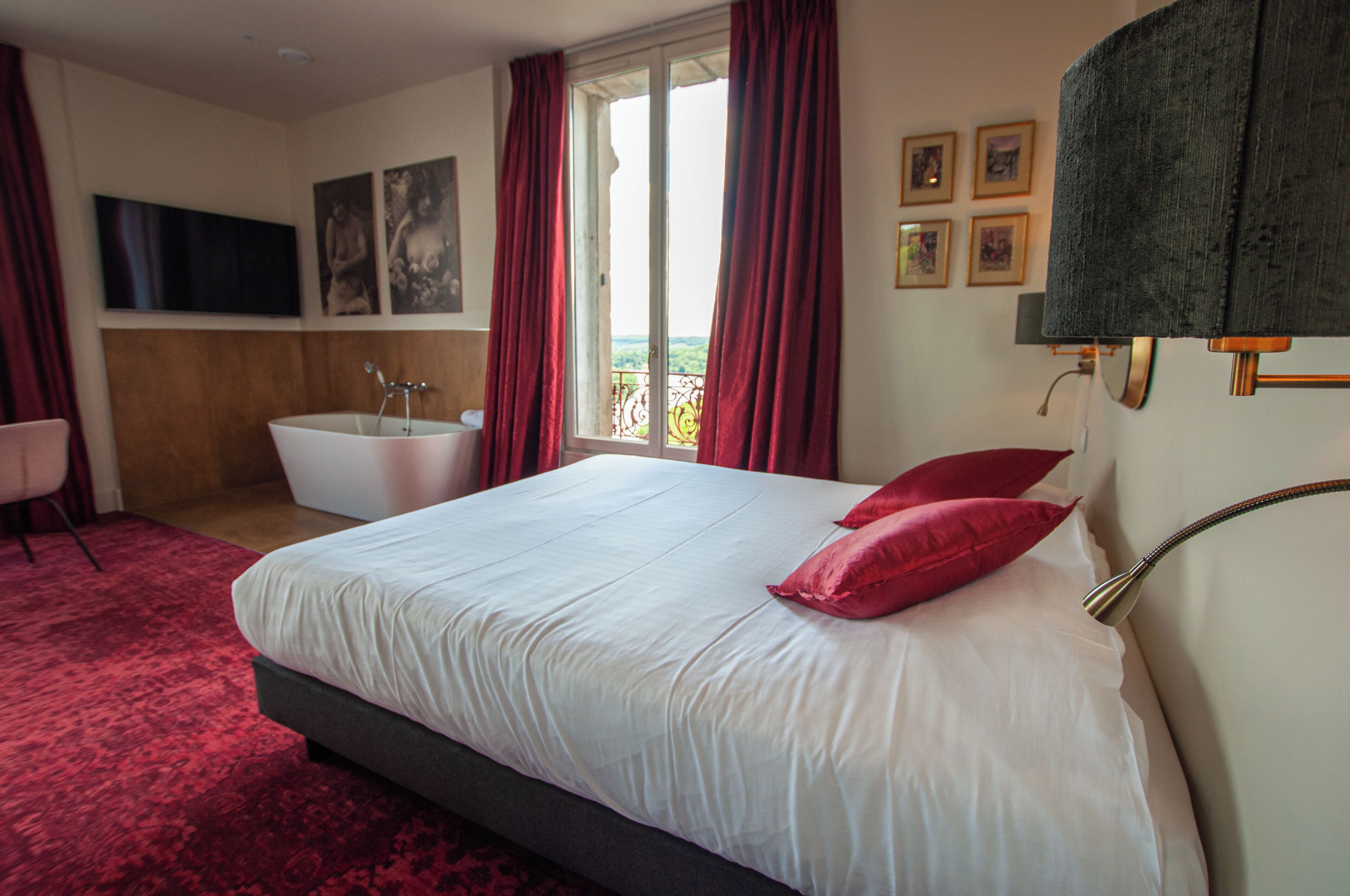 Habitación de hotel con una cama grande, una bañera y vistas al exterior.