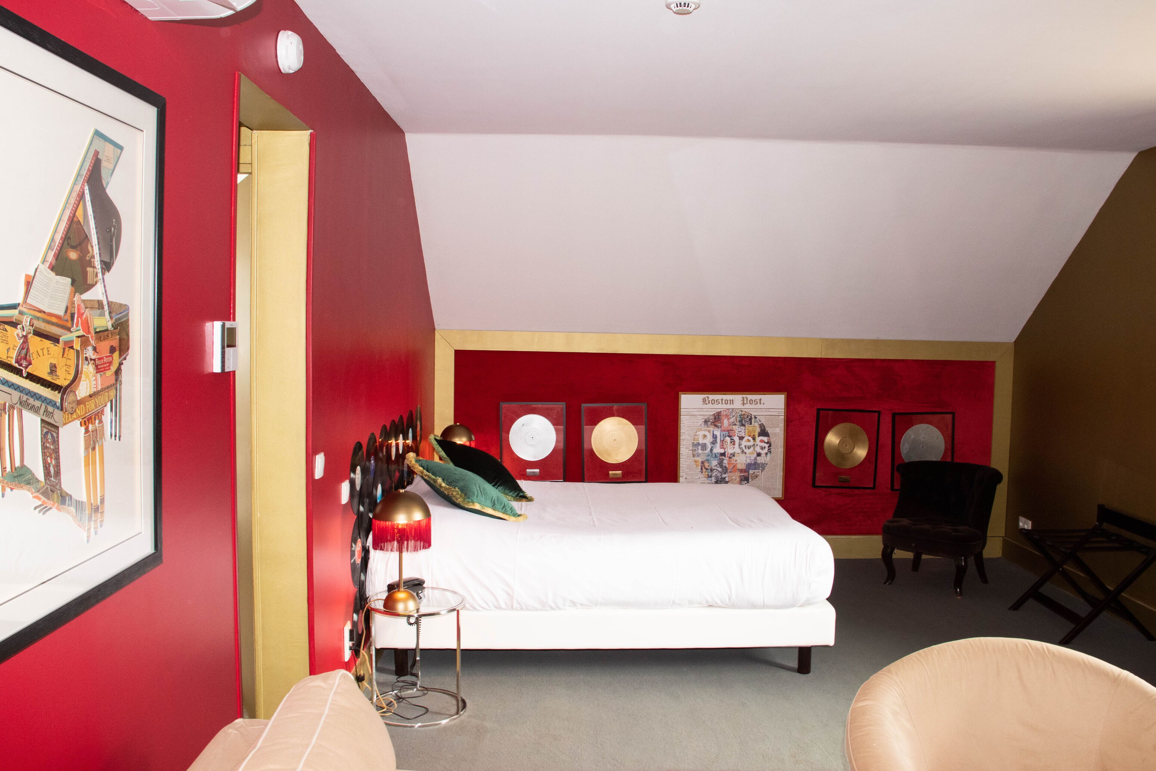 A bedroom with a bed, a chair, a desk, and a framed picture on the wall.