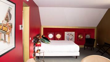 A bedroom with a bed, a chair, a desk, and a framed picture on the wall.