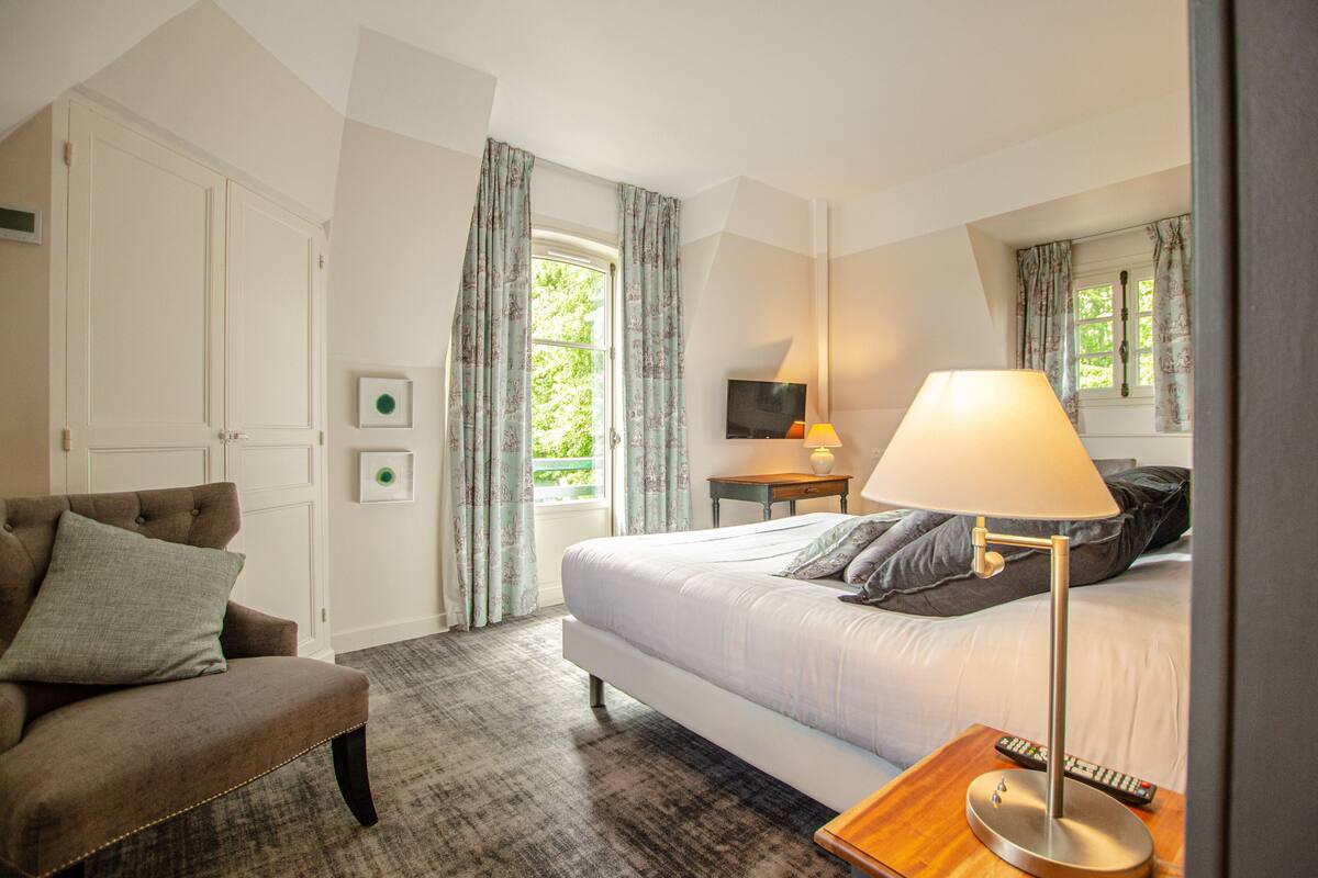 Ein Hotelzimmer mit Bett, Stuhl, Schreibtisch mit Lampe und Fernseher.