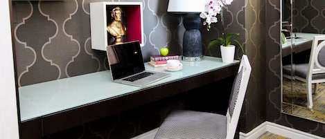 Un espacio de trabajo moderno con una computadora portátil, libros, una lámpara y objetos decorativos sobre un escritorio.