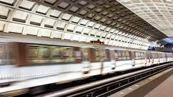 A subway station with a tiled ceiling and a moving train.