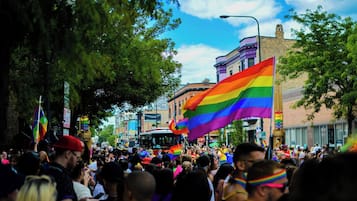 A crowded street with people holding rainbow flags, indicating a public event or parade.
