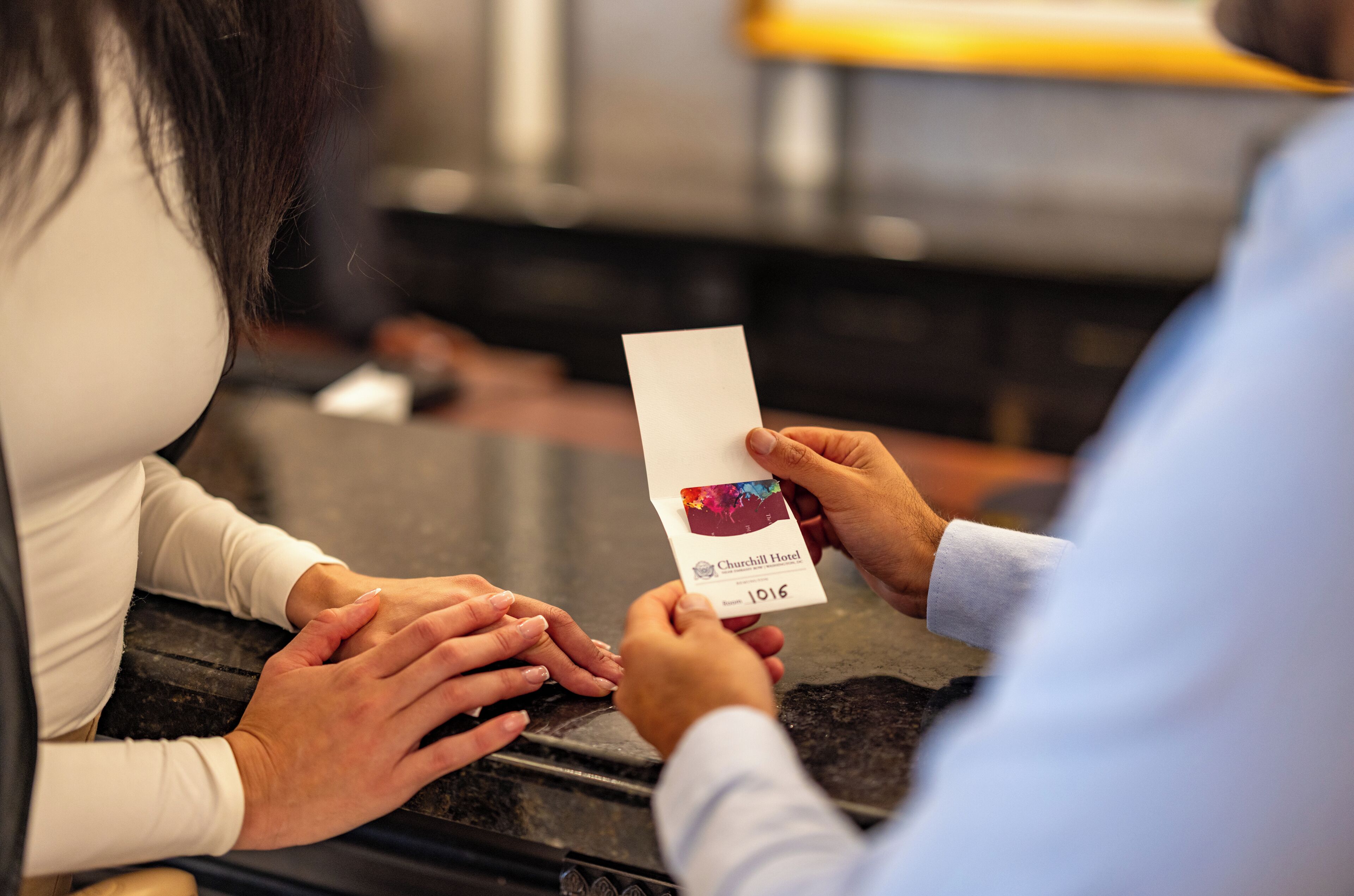A person holding a paper with a hotel name and room number.