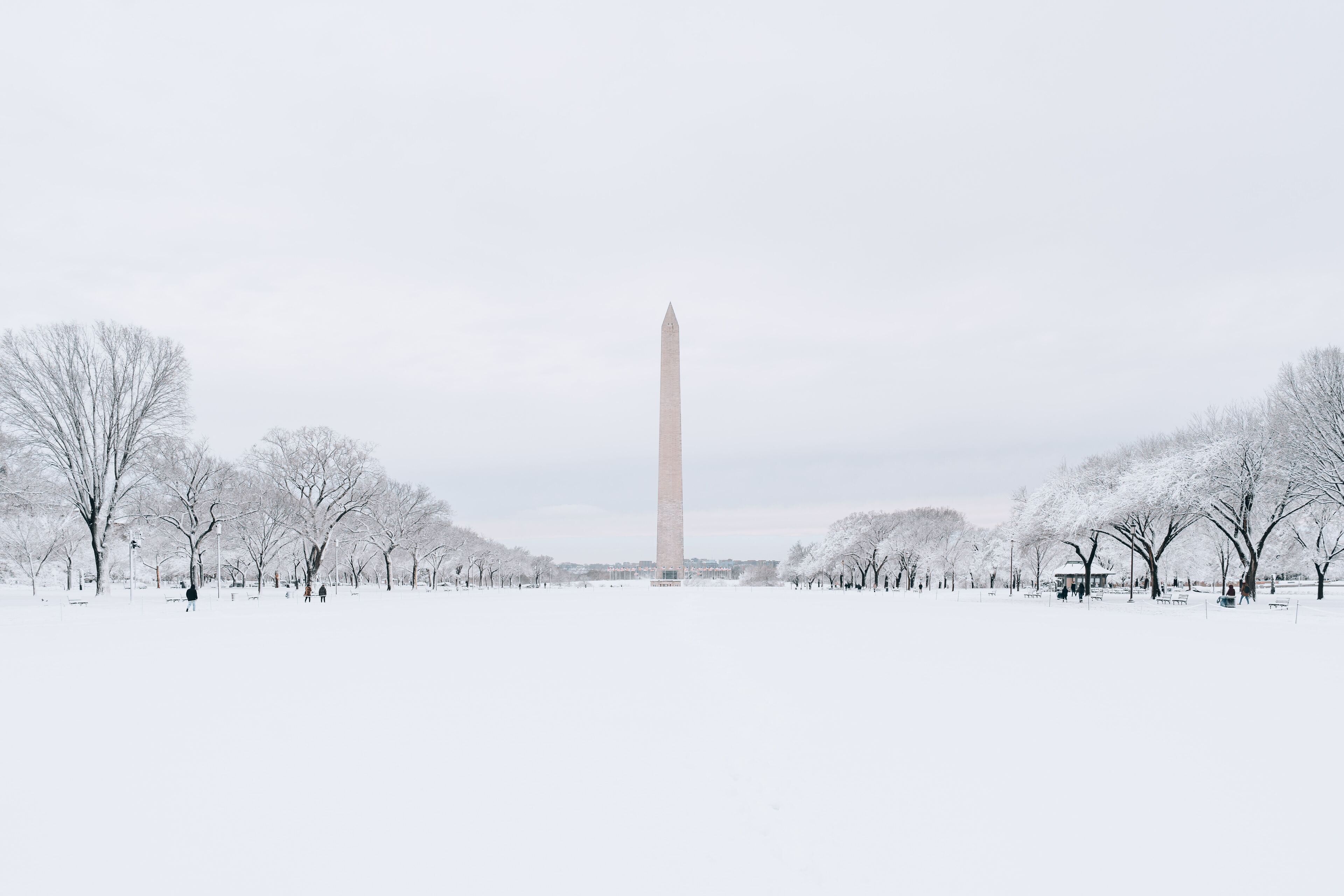Un parque cubierto de nieve con un monumento alto en el centro.
