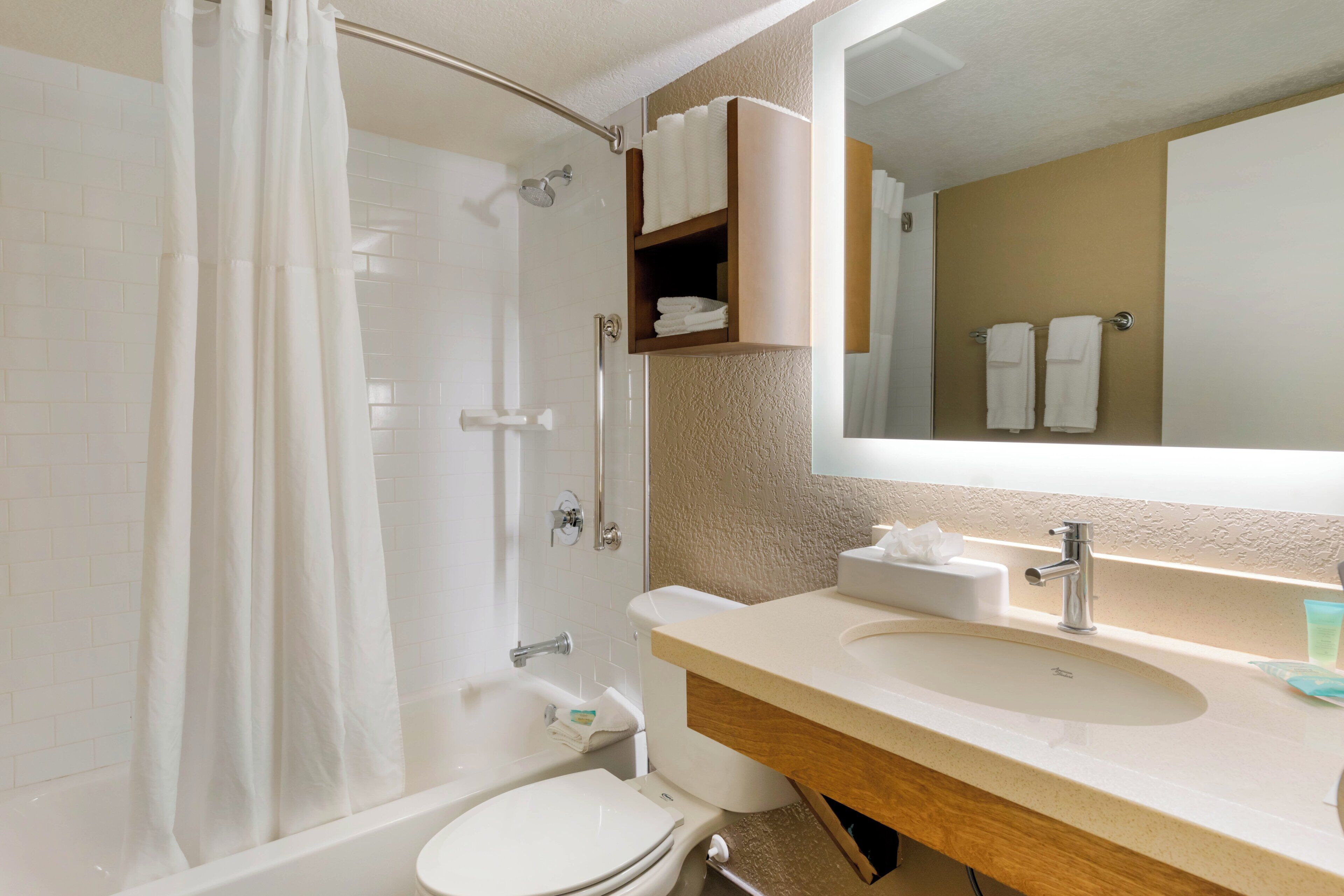 Ein Badezimmer mit Dusche, Toilette, Waschbecken und Spiegel.
