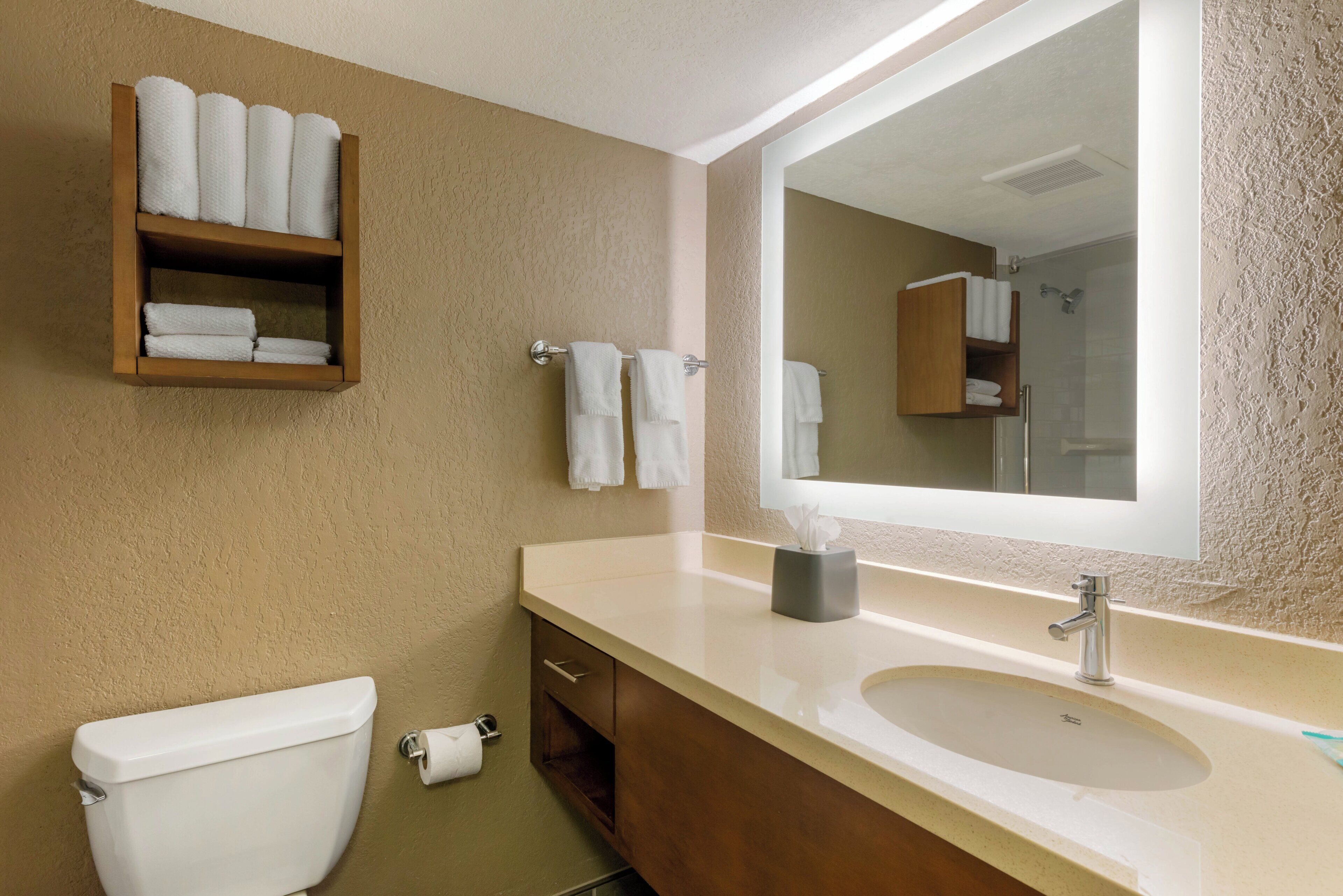 Une salle de bain comprenant des toilettes, un lavabo, un miroir et un porte-serviettes.