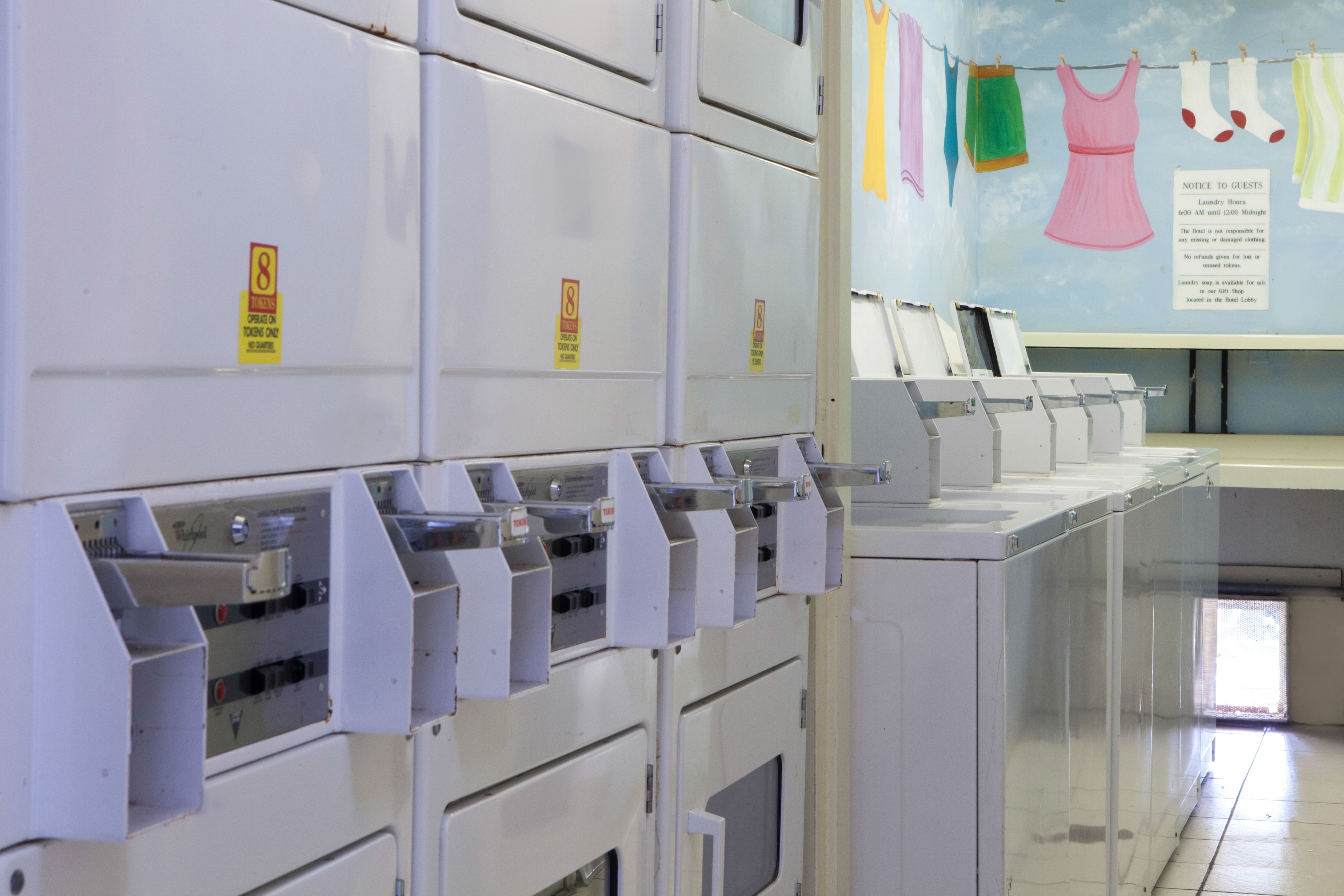 A laundry area with multiple washing machines and a notice about laundry hours.