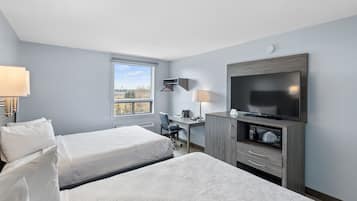 Habitación de hotel con dos camas, un escritorio, un televisor y ventana con vista.