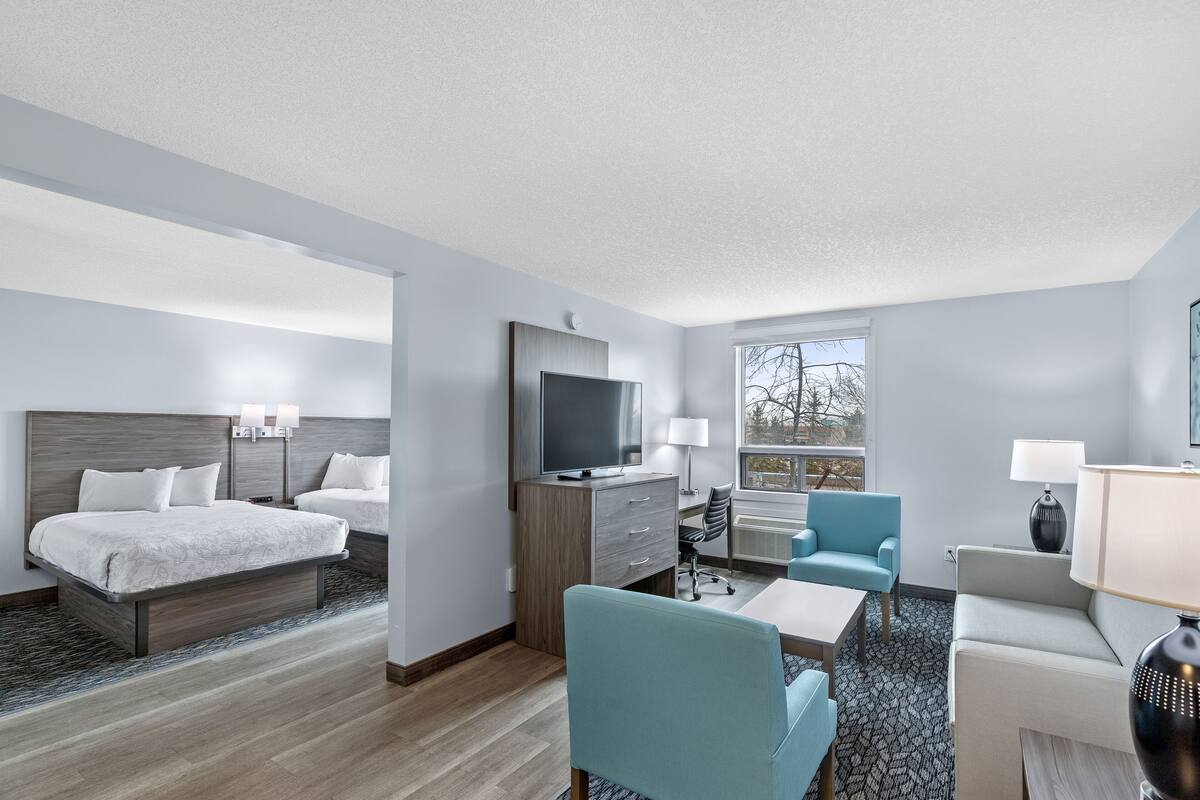 Une chambre d’hôtel avec un lit, un bureau, une chaise, une télévision et une fenêtre.