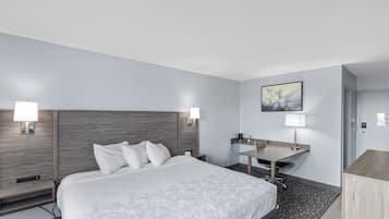 A modern hotel room with a large bed, bedside tables, a desk, and a chair.