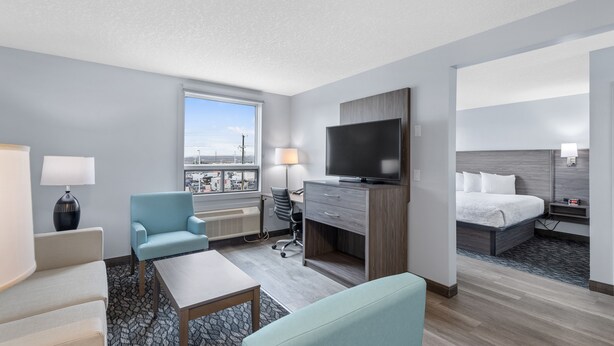 Une chambre d’hôtel avec un lit, un bureau avec une télévision, une chaise, une lampe et une vue sur la ville.