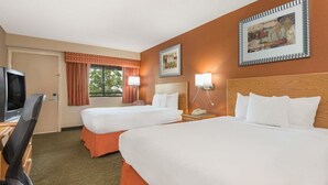 A hotel room with two beds, a desk with a TV, and a window with curtains. - Days Inn by Wyndham Columbus Fairgrounds (Columbus)