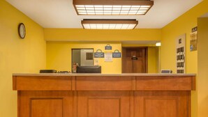 A reception desk with a clock, a sign indicating smoking rules, and a directory on the wall.