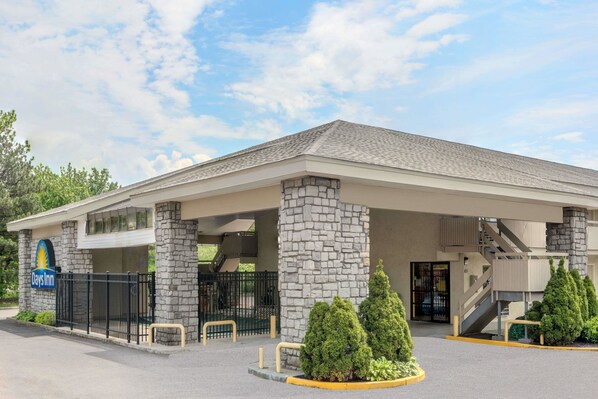 Experience the sleek design of this hotel, featuring a flat roof and covered outdoor seating area with a staircase to an upper level.