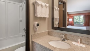 A bathroom with a sink, mirror, towel rack, and a shower.