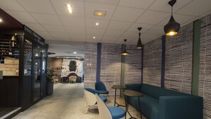 Un intérieur moderne avec un coin salon comprenant un canapé bleu et deux fauteuils, une petite table et un présentoir à vin.