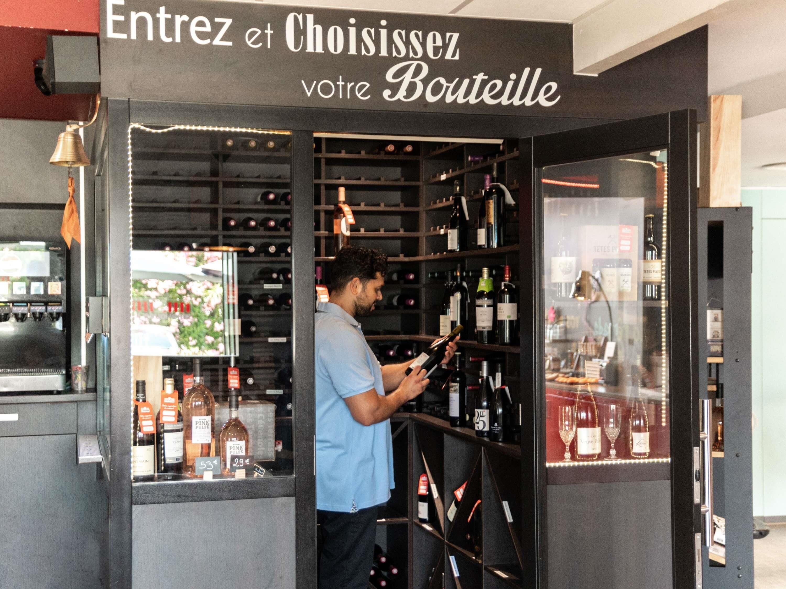 Interior de una tienda de vinos con estantes llenos de botellas y una persona mirando.