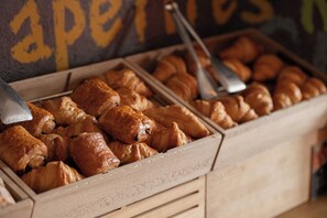 A wooden display case filled with assorted pastries, including croissants and other baked goods. - ibis Narbonne (Narbonne)