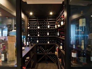A wine cellar with multiple shelves of wine bottles, a wooden counter, and a glass door. - ibis Narbonne (Narbonne)