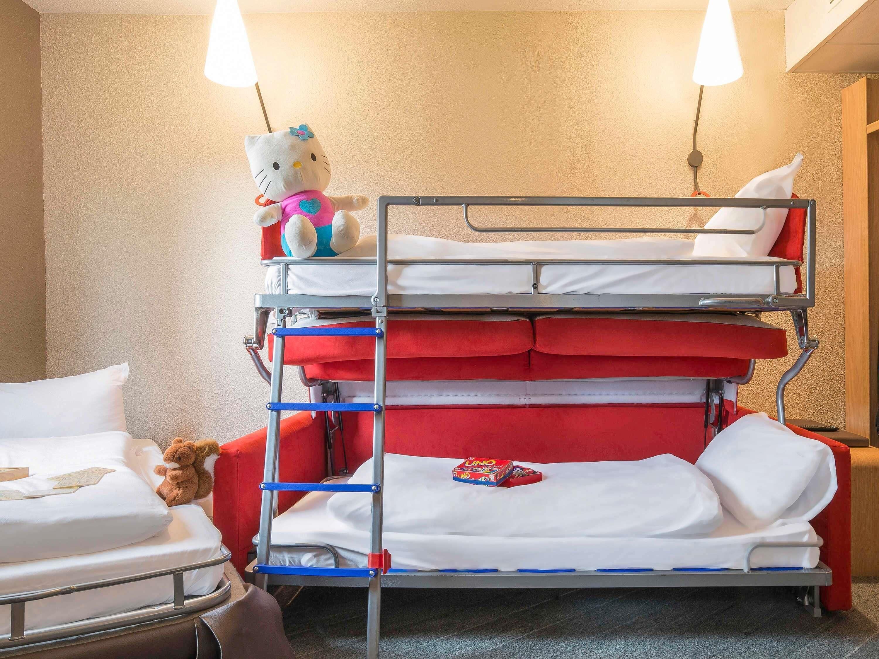 A bunk bed with a Hello Kitty plush toy on the top bunk and a UNO game box on the lower bunk.