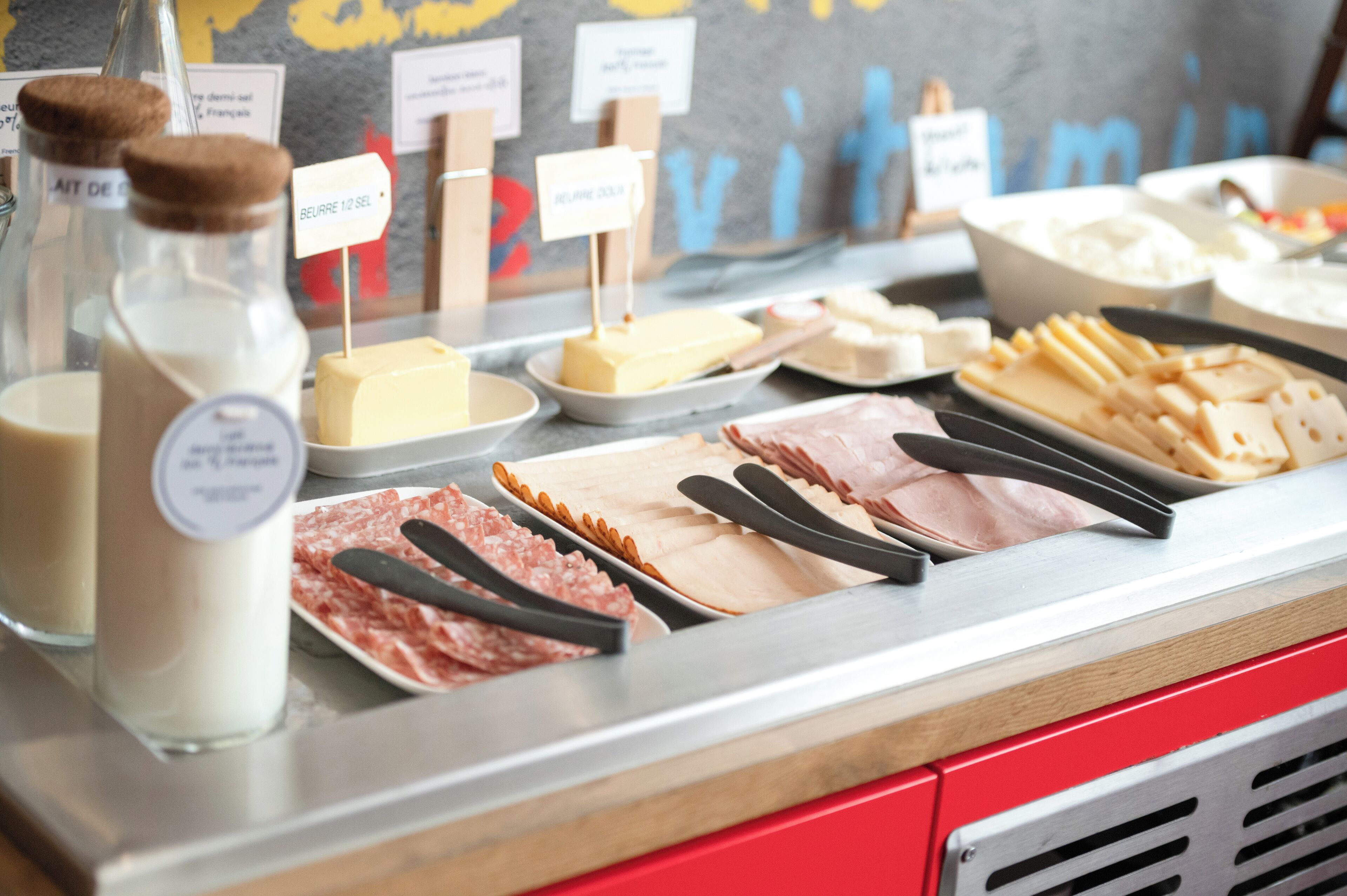 A buffet with various food items including cheese, meats, and dairy products.