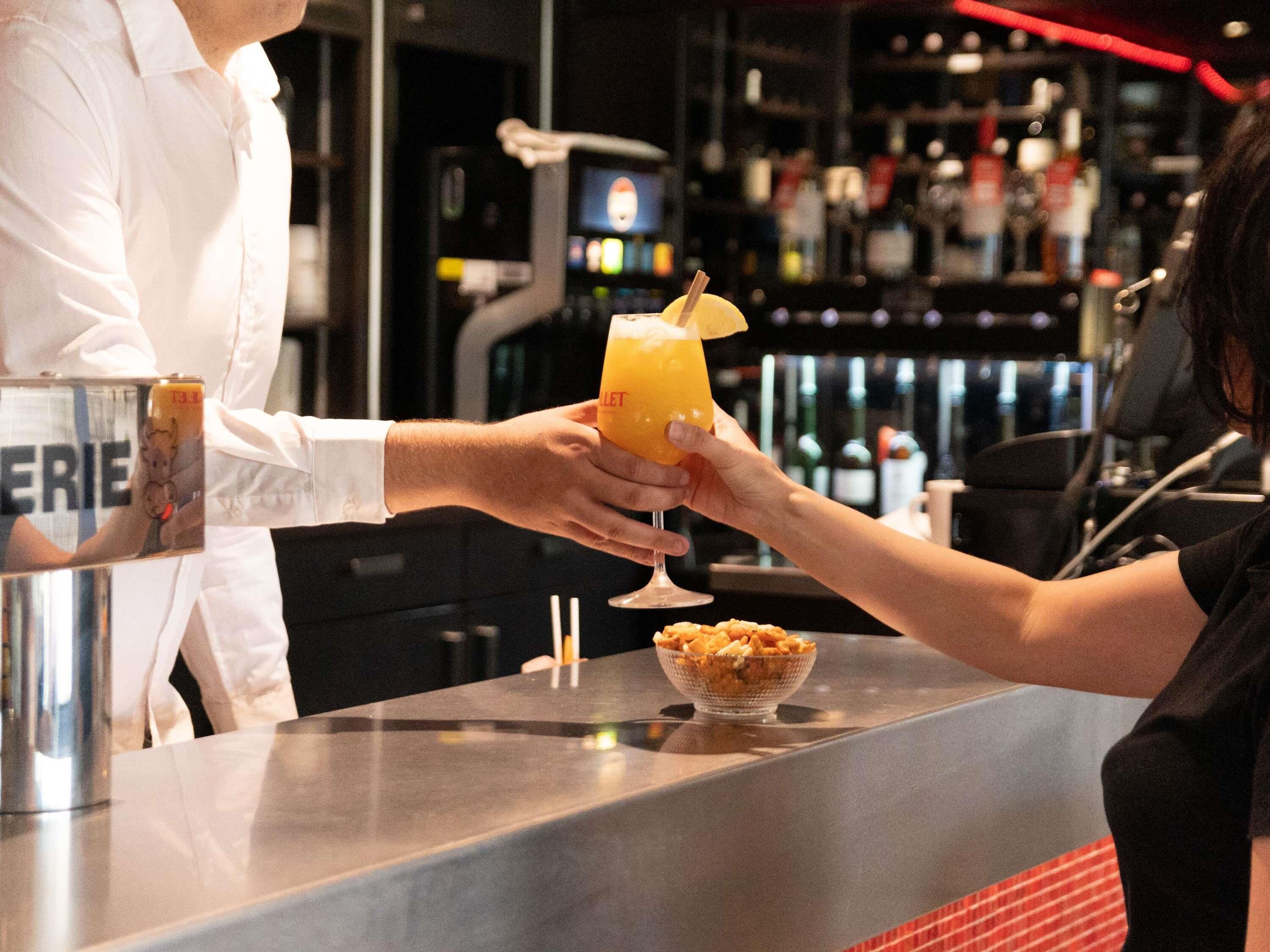 A bar setting with a person holding a cocktail glass.