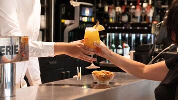 A bar setting with a person holding a cocktail glass.