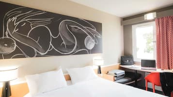 A hotel room with a bed, desk, chair, and a large abstract painting on the wall.