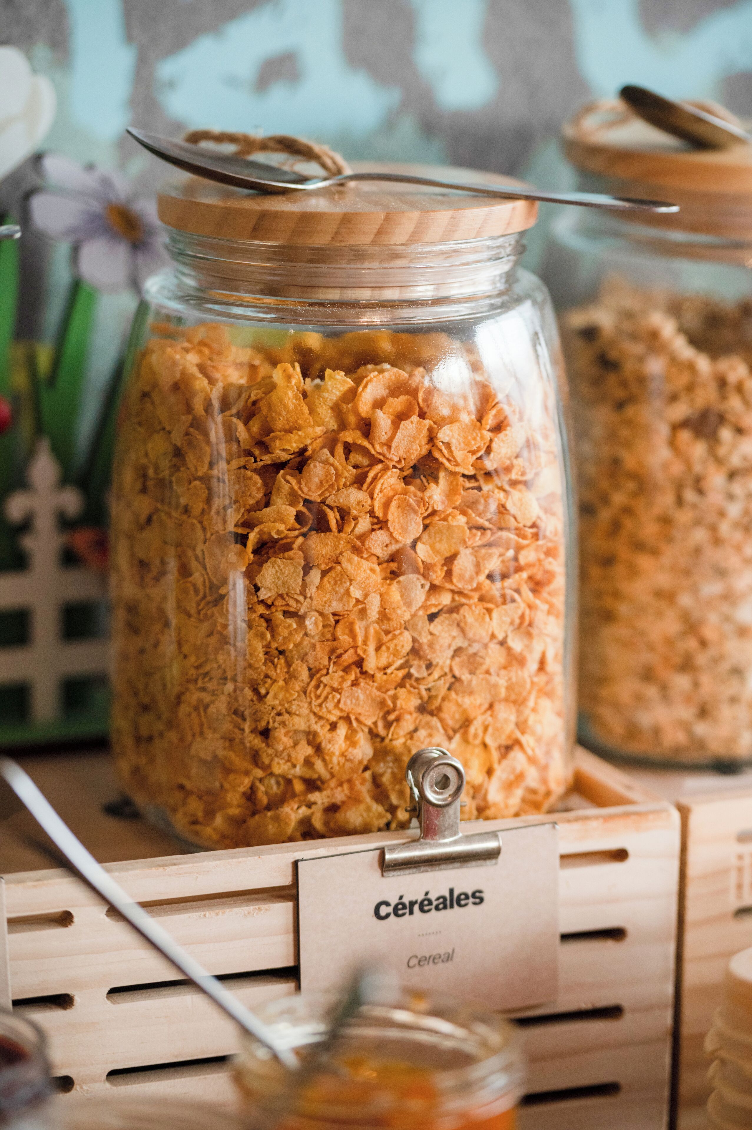 A glass jar filled with cereal, placed on a wooden stand with a label reading "céréales".
