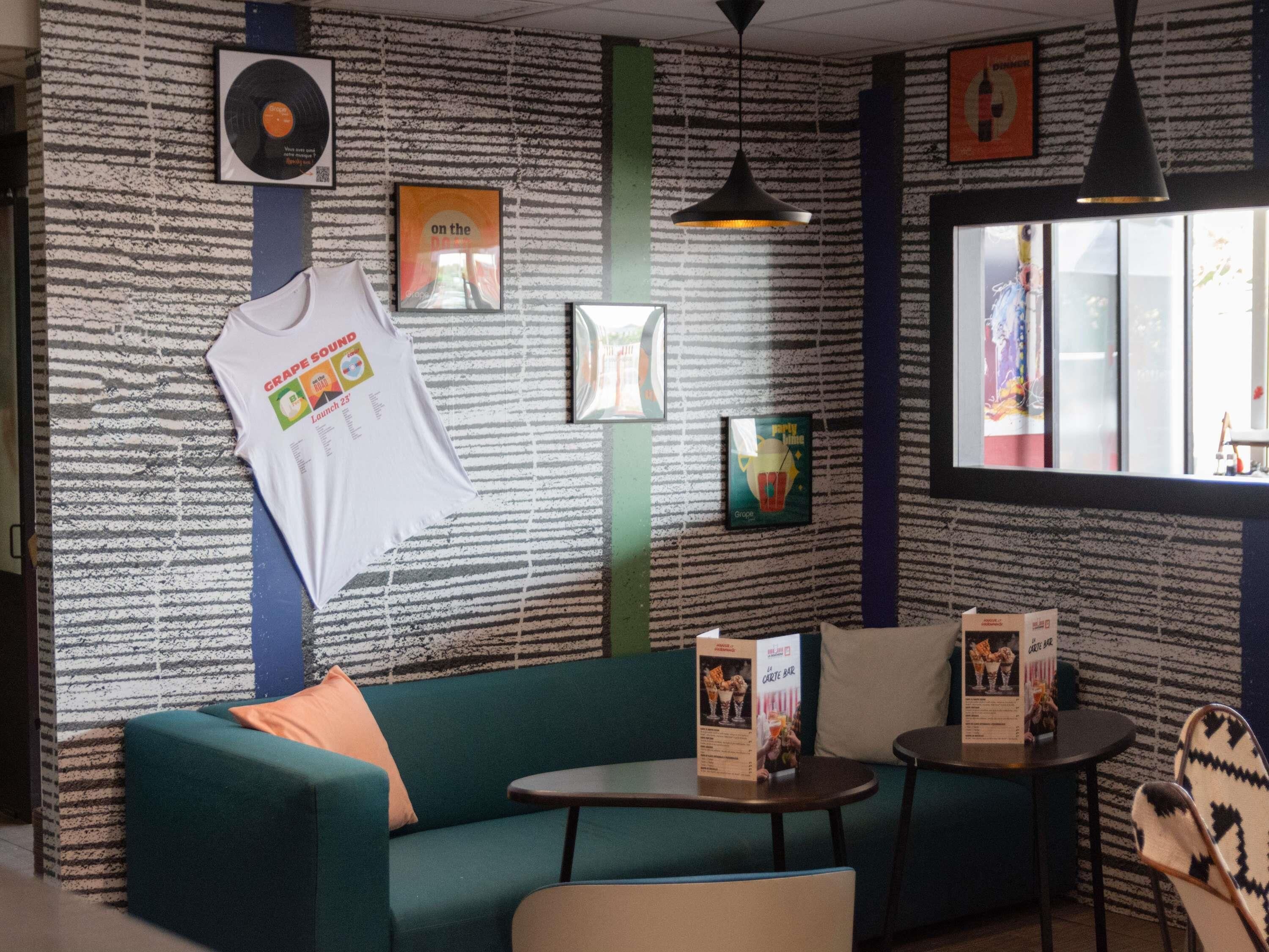 A cozy room with a green sofa, a small table, and a hanging t-shirt.