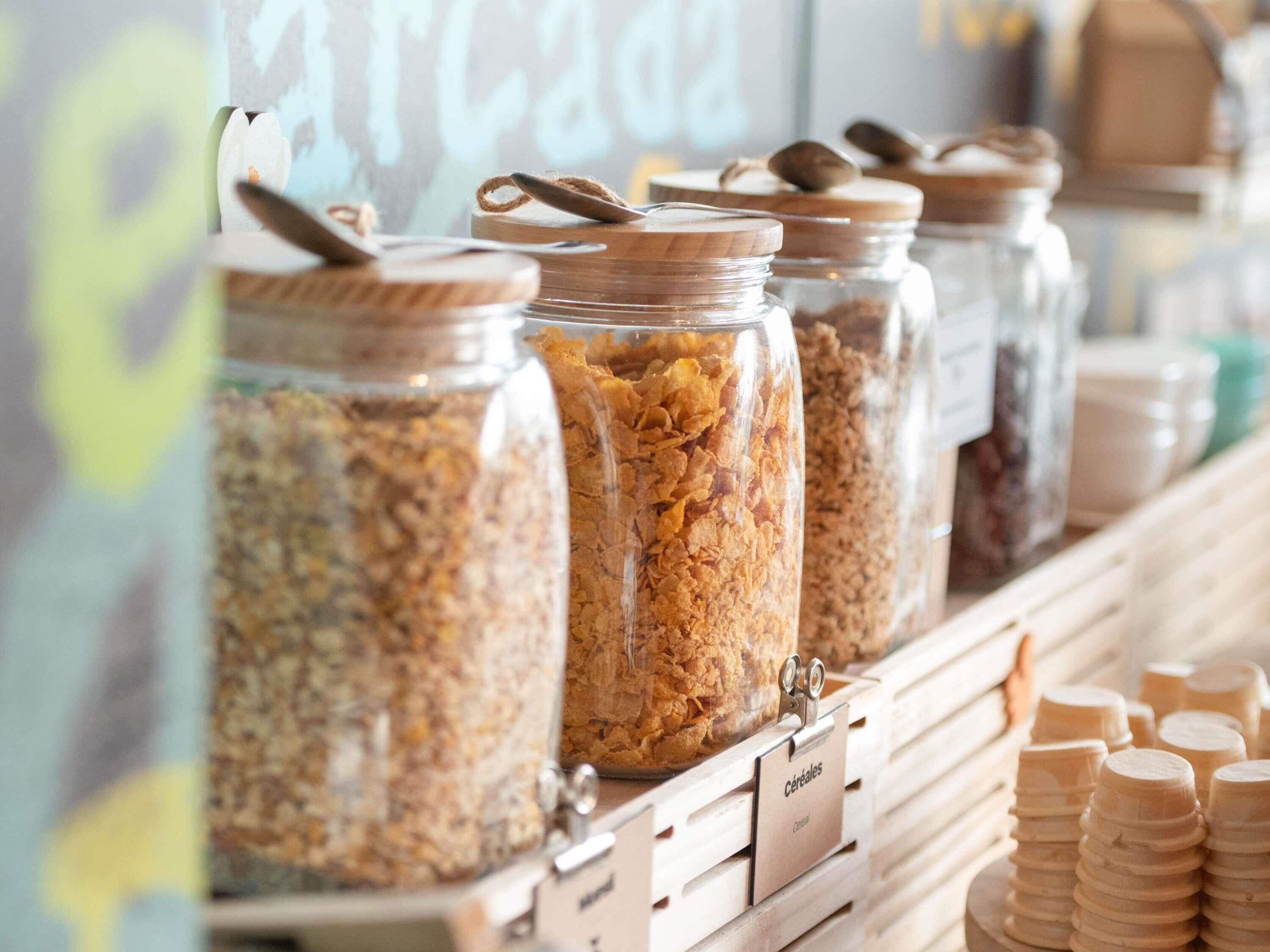 A food display with jars of cereal and wooden scoops.