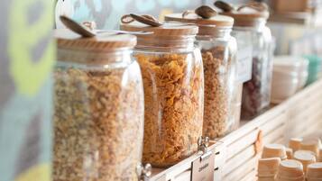 A food display with jars of cereal and wooden scoops.