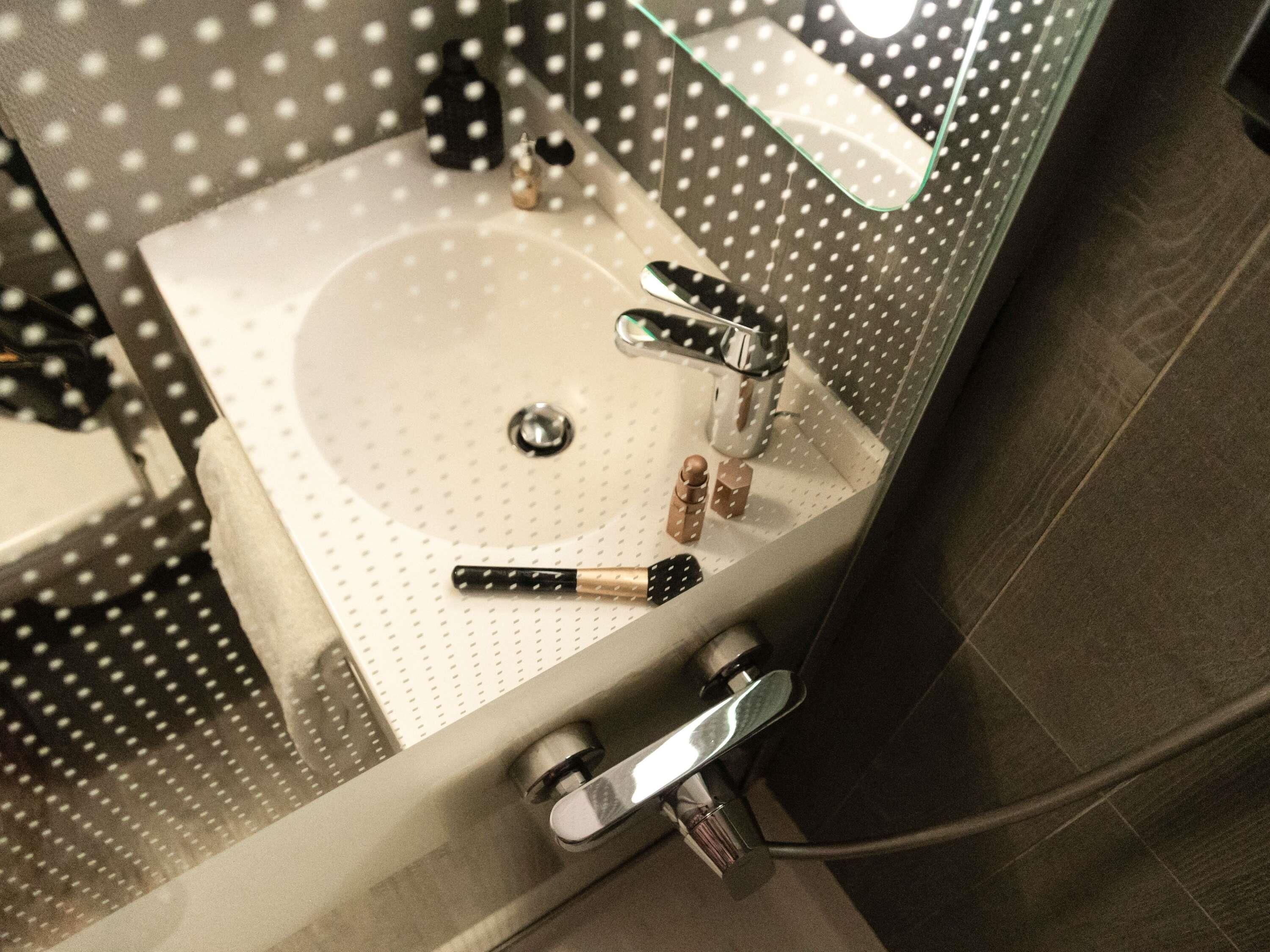 A bathroom with a white sink, a mirror, and a shower area.
