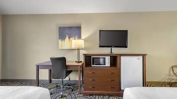 A hotel room with two beds, a desk with a chair, a television, a microwave, and a refrigerator.