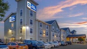 Un hotel Best Western con varios pisos, un estacionamiento con varios coches y una entrada cubierta.