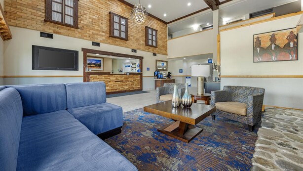 Un hall espacioso con un sofá azul, alfombra estampada y una mesa de centro de madera.