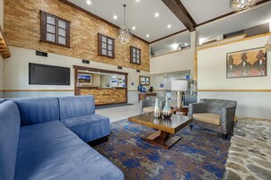 A spacious lobby with a blue sofa, patterned rug, and a wooden coffee table.