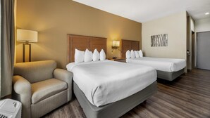 Habitación de hotel con dos camas, un sofá, una lámpara y un cuadro en la pared.