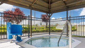 Una piscina techada con baranda metálica, una silla de salvavidas azul y vistas despejadas de la vegetación y árboles circundantes.